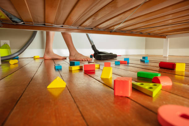 Feet of boy clean floor with mess under the bed stock photo