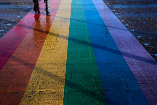 pies de pareja caminando sobre asfalto con los colores de la bandera lgbt - nyc pride parade fotografías e imágenes de stock