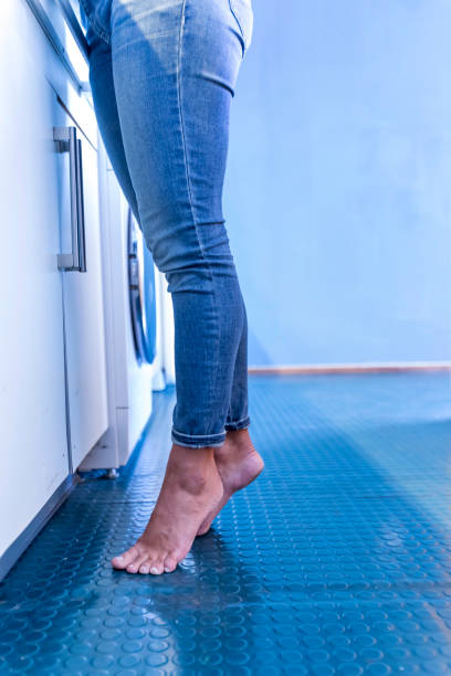 Feet of woman standing on tiptoe at home in the kitchen stock photo