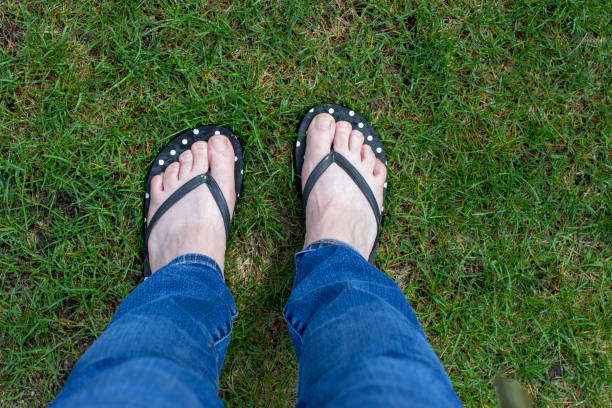 Feet wearing flip flops in wet grass Woman's feet wearing polka dot flip flops on wet grass kathrynsk stock pictures, royalty-free photos & images