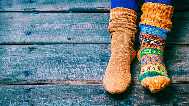Feet wearing socks Female feet wearing odd wool socks on the wooden floor. Closeup view sock stock pictures, royalty-free photos & images