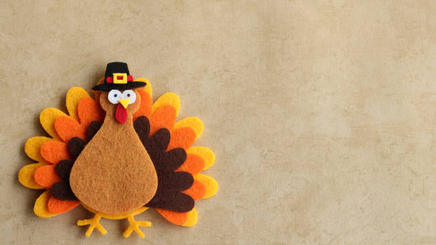 Felt turkey laying flat on a tan background with copy space Orange brown and yellow felt turkey with pilgrim hat on a tan background with writing space thanksgiving stock pictures, royalty-free photos & images