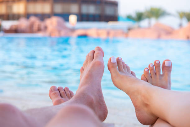 Female amd male pedicured feet near the pool. Body care and chiropody concept. Luxury resort relaxation. man pedicure stock pictures, royalty-free photos & images
