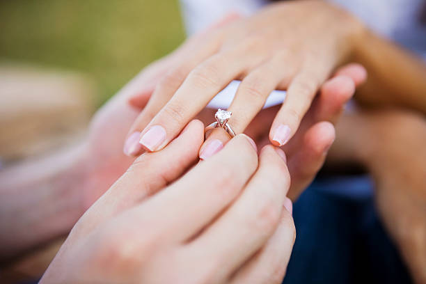 Female and male hands slipping on engagment ring stock photo