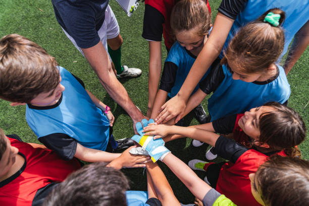 vrouwelijke en mannelijke kinderen voetbalspelers samen met de handen in de cirkel voor een wedstrijd - coach stockfoto's en -beelden