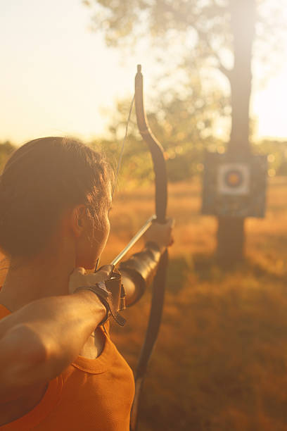 Female archer in the field at sunset stock photo