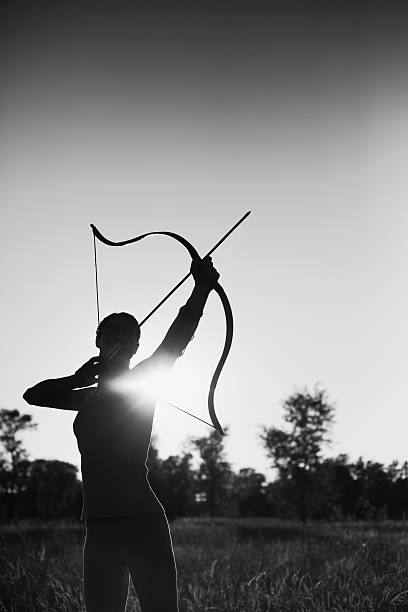 Female archer in the field at sunset stock photo