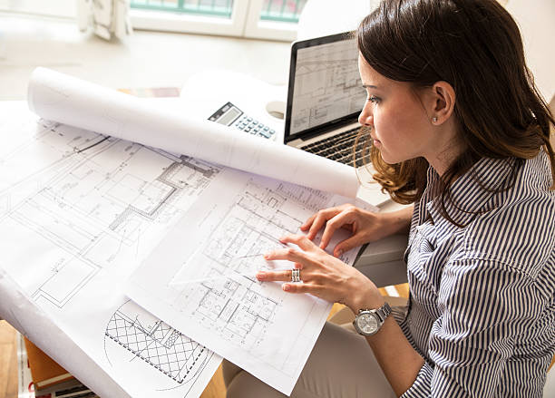 Female architect Female architect working at home.She looking at blueprint. architect stock pictures, royalty-free photos & images
