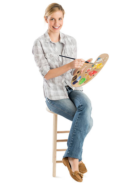 Female Artist With Palette And Paintbrush Sitting On Stool stock photo