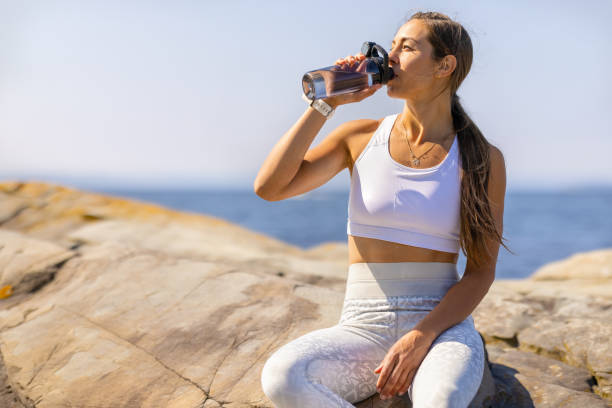 Female Athlete Drinking Water During Outdoor Workout by the Sea stock photo