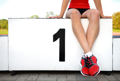 girl wearing spikes (cleats) and waiting in starting block on athletic track