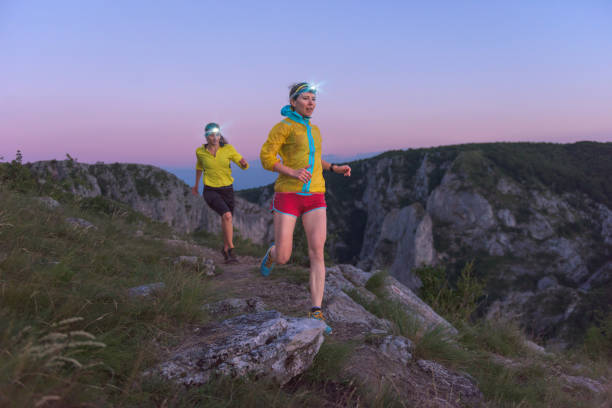 Female athlete running up the hill at sunset stock photo