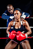 Female boxer getting pep talk by her coach in the ring during a bout.