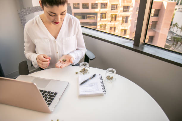 Female Cannabis Entrepreneur holding a Bud, Working on Marketing for Marijuana Business in Bright, Soft Lit Office stock photo