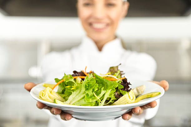 Female chef presenting salad stock photo