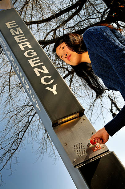 Female College Student Calling for Help "Chinese-born American girl, 19, and a student. In this scene she stands next to an emergency call station preparing to push the button (eek, some photographer keeps taking my photo)." mike cherim stock pictures, royalty-free photos & images