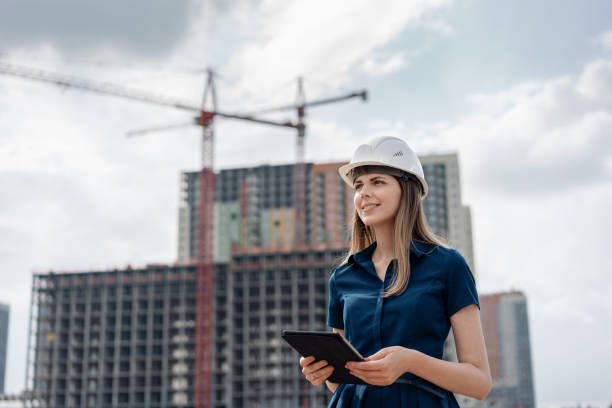 Female construction engineer. Architect with a tablet computer at a construction site. Young Woman looking, building site place on background. Construction concept stock photo