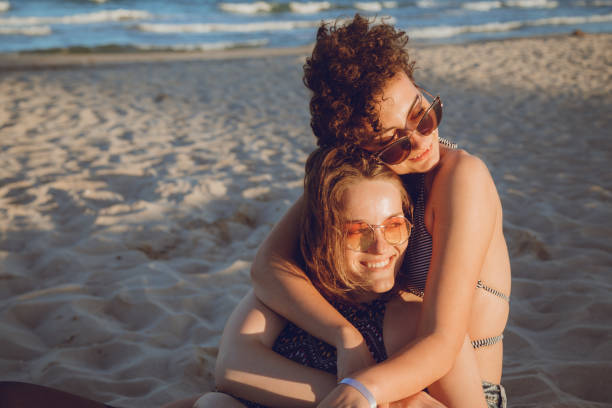 Female couple on the beach Female couple is enjoying beach holiday gay spooning stock pictures, royalty-free photos & images