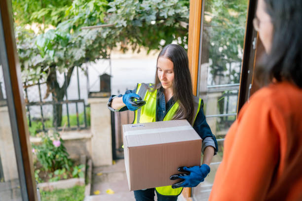 Female delivery person delivering package to customer at home. She is taking photo of bar code with bar code reader A female delivery person is delivering a package to a customer at home. She is taking A photo of bar code with a bar code reader. yalla shoot koora stock pictures, royalty-free photos & images
