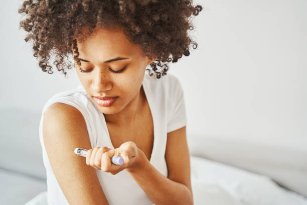 Female diabetic injecting insulin into her upper arm stock photo