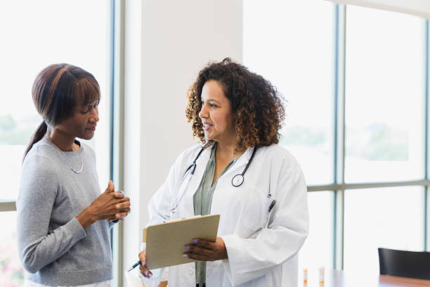 Female doctor and senior patient discuss medical records stock photo