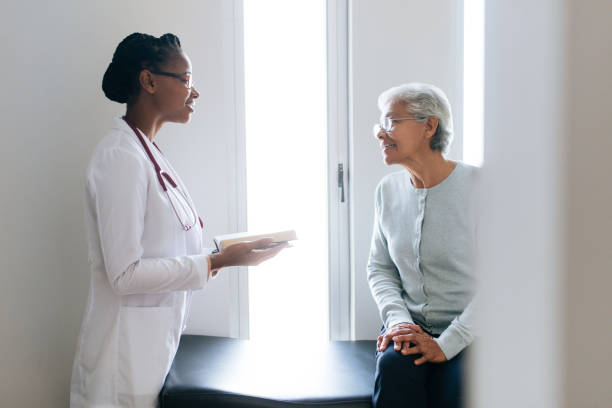 Female doctor consulting senior patient A black female doctor consulting a senior female patient at the doctor's office, looking at each other and smiling. beautiful haitian women stock pictures, royalty-free photos & images