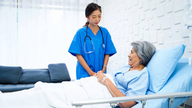 Female doctor enters patient room to inquire about the symptoms of an elderly woman who was receiving saline in a bed in the patient room. Female doctor enters patient room to inquire about the symptoms of an elderly woman who was receiving saline in a bed in the patient room. Female doctor talking to female patient about better. physical therapy programs stock pictures, royalty-free photos & images
