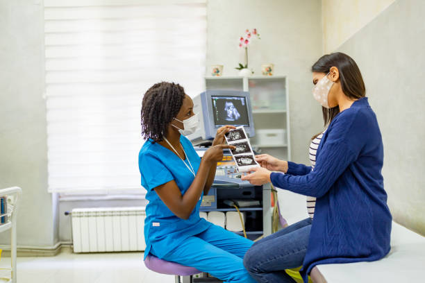 Female doctor explaining ultrasound photos to a pregnant woman stock photo