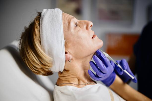 Female doctor giving patient lipolysis double chin treatment stock photo
