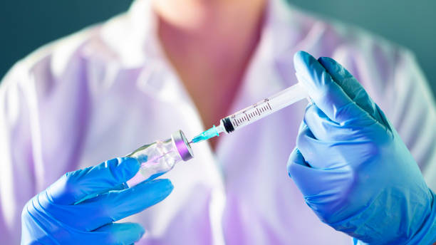female Doctor hand holding syringe and covid-19 vaccine in blue gloves with white coat. Disease injection concept. female Doctor hand holding syringe and covid-19 vaccine in blue gloves with white coat. Disease injection concept. dose stock pictures, royalty-free photos & images