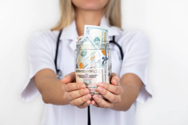 Female Doctor Holding Piggy Bank. Doctor's hands close-up. Medical insurance and health care concept. stock photo
