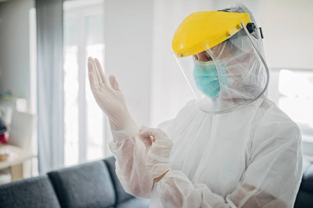 Female doctor in full protective suit in home inspection One woman, female doctor in full protective suit in home inspection. protective workwear stock pictures, royalty-free photos & images