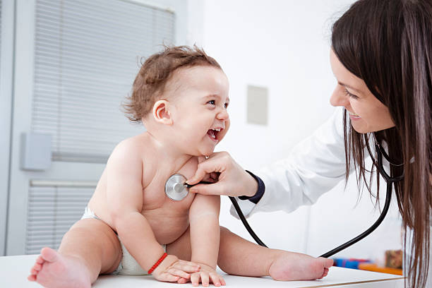 Female doctor listening to smiling baby's heartbeat Doctor checking up baby with stethoscope. pediatrician stock pictures, royalty-free photos & images