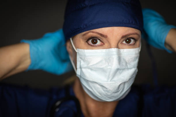 Female Doctor or Nurse Wearing Surgical Gloves Putting On Medical Face Mask Female Doctor or Nurse Wearing Surgical Gloves Putting On Medical Face Mask. frontline worker stock pictures, royalty-free photos & images