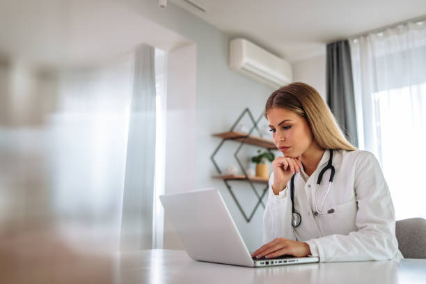Female doctor, searching something online, over the laptop. stock photo
