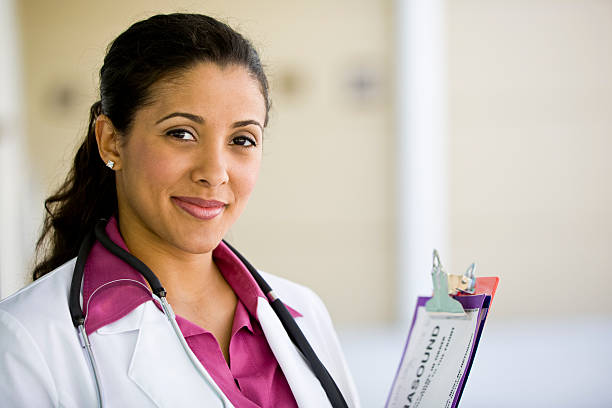 Female doctor smiling and holding patients notes stock photo