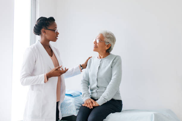 Female doctor standing next to senior patient and talking to her A black female doctor standing face to face with a senior female patient and talking to her in doctor's office. beautiful haitian women stock pictures, royalty-free photos & images