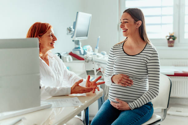 Female doctor talking to pregnant woman in office stock photo
