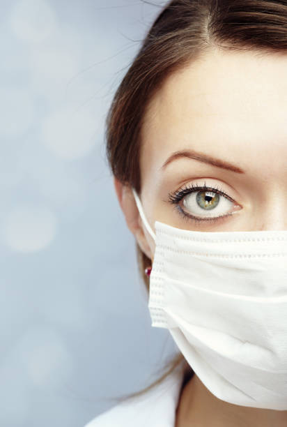 Female doctor wearing protective  face mask against light blue background stock photo