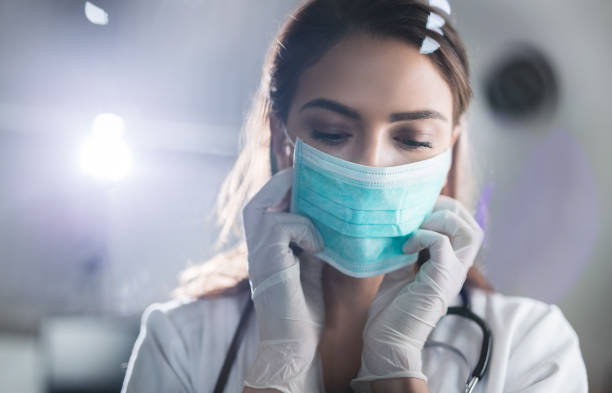 vrouwelijke arts met beschermend masker - besmettelijke ziekte stockfoto's en -beelden