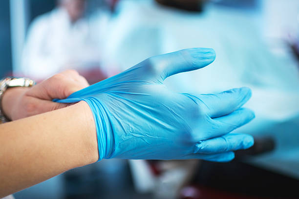 Female doctor's hands putting on blue sterilized surgical gloves. stock photo