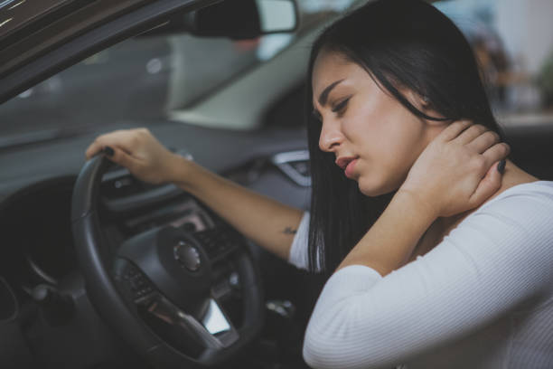 Female driver rubbing her aching neck after long drive Beautiful young woman rubbing her neck, feeling sore after long drive. Female driver having terrible neck pain after whiplash injury in car crash. Healthcare, safety, pain concept physical injury stock pictures, royalty-free photos & images