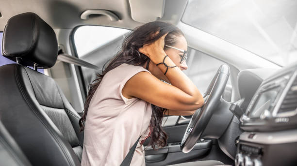 Female driver with headache or in desperation holds her head with both hands sitting on a driver's seat. stock photo