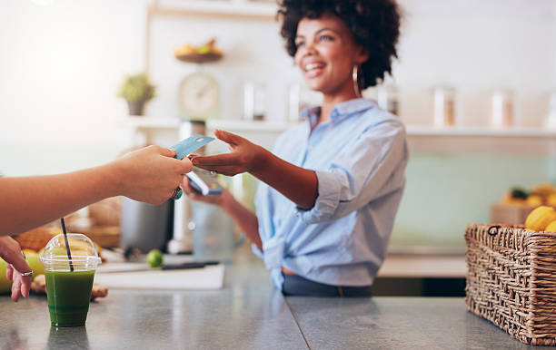 Female employee taking payment from customer Cropped shot of female employee taking payment from customer, focus on female hands giving credit card for juice bar payment. credit card purchase stock pictures, royalty-free photos & images