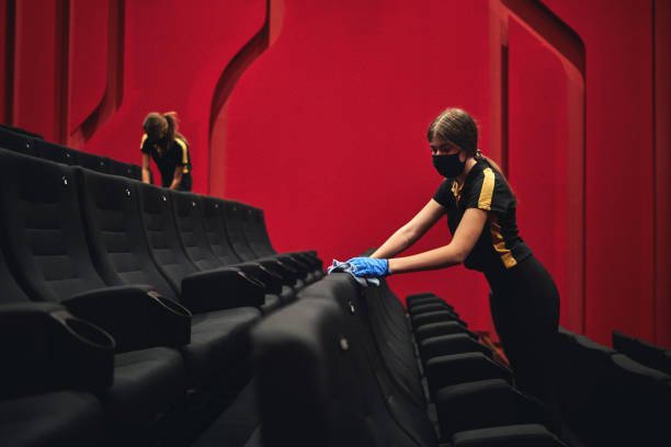 Female Employees Disinfecting Movie Theater Seats Before Reopening After Coronavirus Pandemic Female employees disinfecting movie theater seats before reopening after coronavirus pandemic. movie theater cleaning stock pictures, royalty-free photos & images