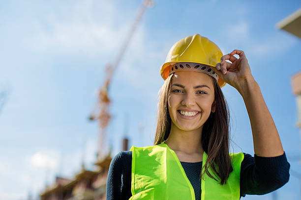 Female engineer lifting her yellow helmet stock photo