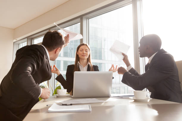 Female entrepreneur meditating during hard meeting Beautiful funny businesswoman keeping calm in stressful situation at work, refusing pay attention to difficulties or misunderstanding during negotiations, ignoring excited angry colleagues on meeting angry vs calm leader stock pictures, royalty-free photos & images