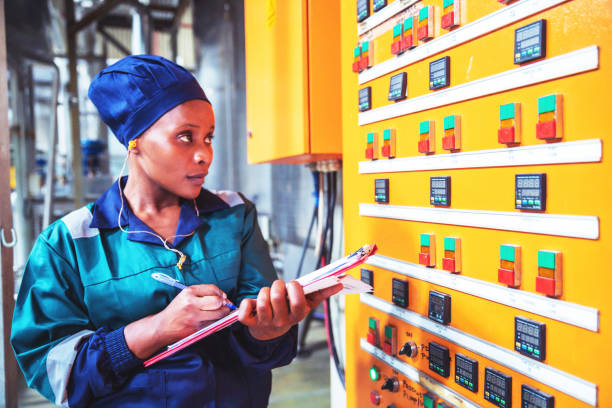 Female Factory Engineer Checking the Electrical Panel Factory, Inspection, Supervisor, Training - Electrical Engineer at a factory writing down the reading from the electrical panel developing countries stock pictures, royalty-free photos & images