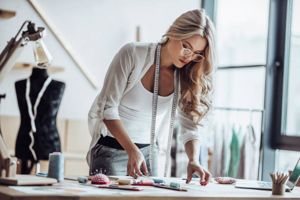 Female fashion designer Attractive female fashion designer is working in her workshop. Stylish woman in process of creating new clothes collection. tailor stock pictures, royalty-free photos & images