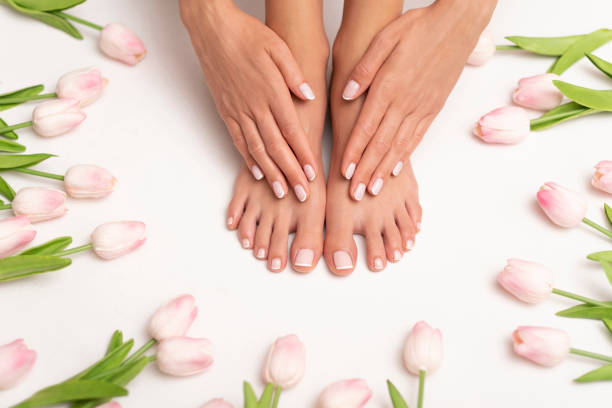 Female feet and hands with perfect pedicure surrounded by tulips. Spa time. Pedicure and manicure. toenail stock pictures, royalty-free photos & images